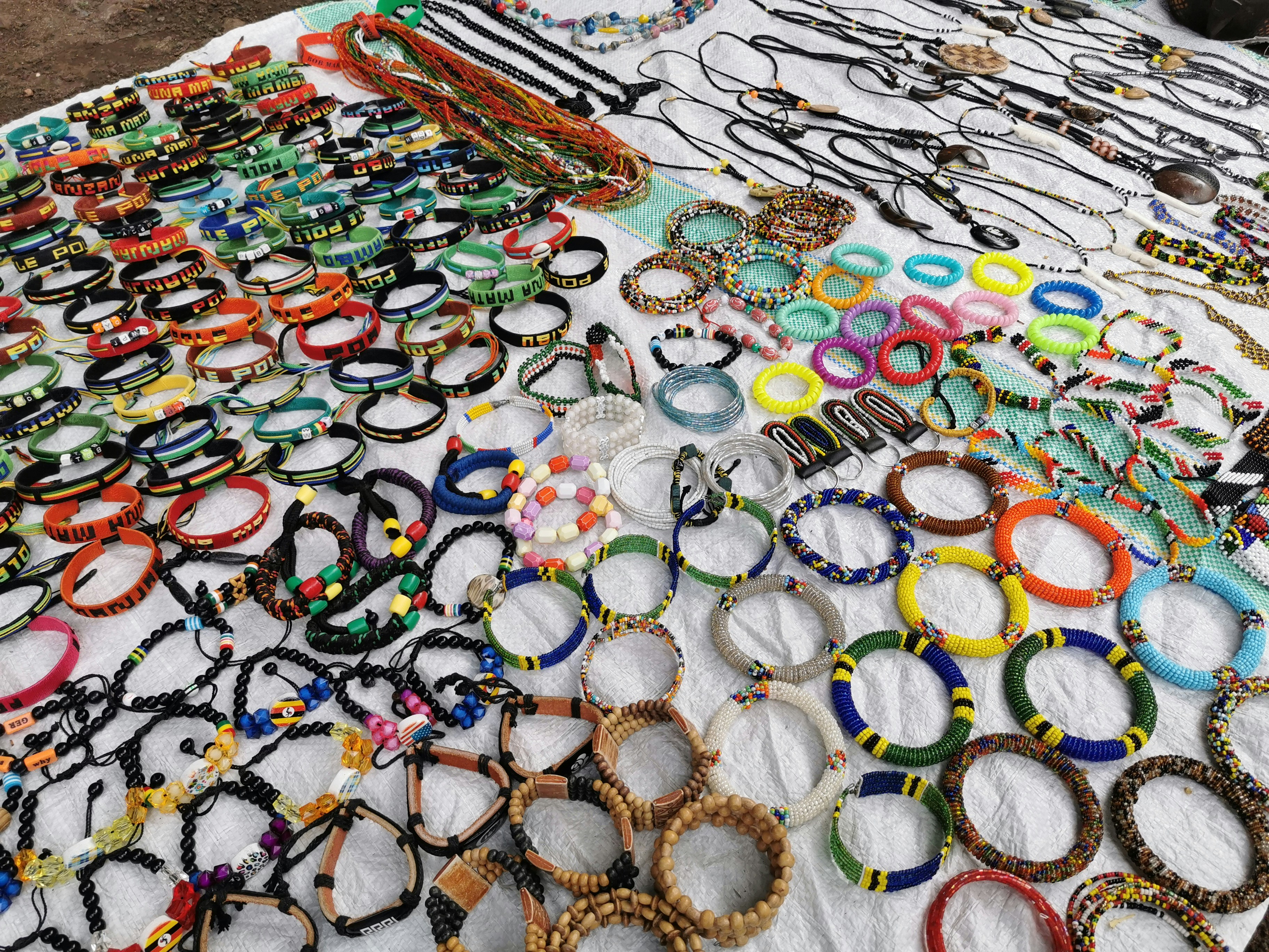 Colorful handmade bead jewelry and accessories with pastel beads arranged on white surface