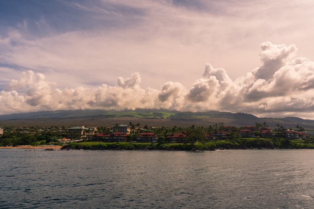 body of water near green trees under white clouds during daytime