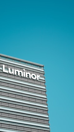 A modern office building facade featuring horizontal lines and large windows, with the word 'Luminor' prominently displayed.