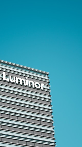 A modern office building facade featuring horizontal lines and large windows, with the word 'Luminor' prominently displayed.
