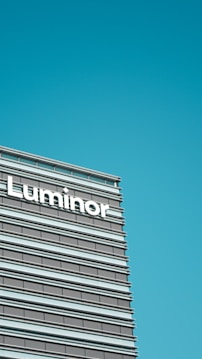 A modern office building facade featuring horizontal lines and large windows, with the word 'Luminor' prominently displayed.
