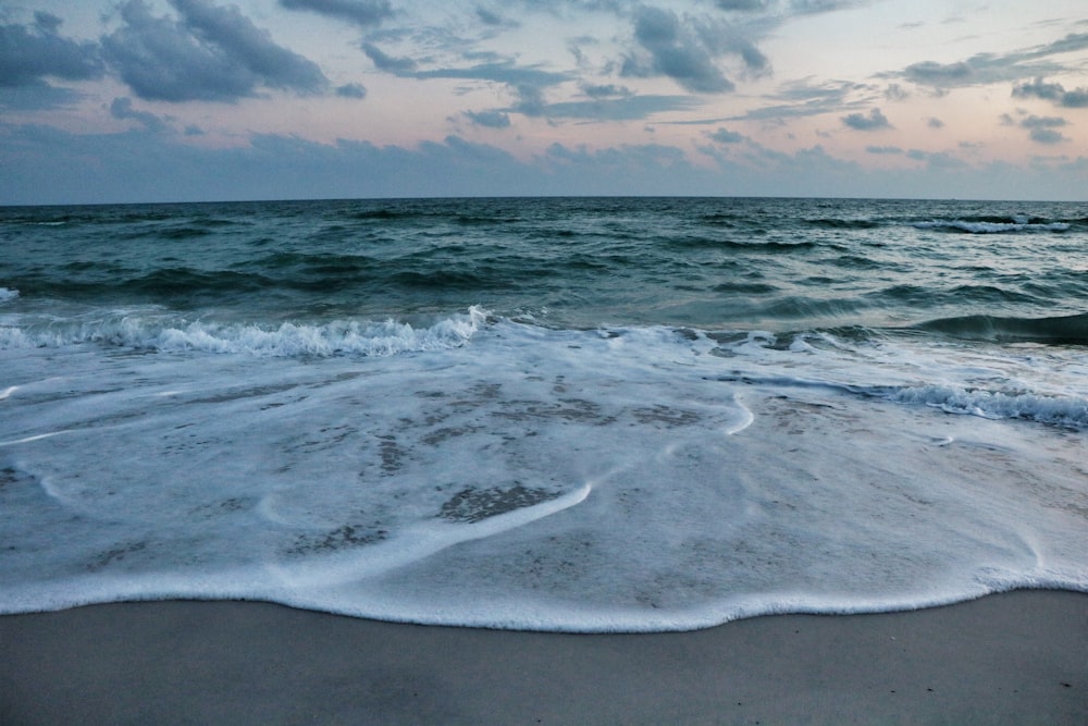 ocean waves crashing on shore during sunset