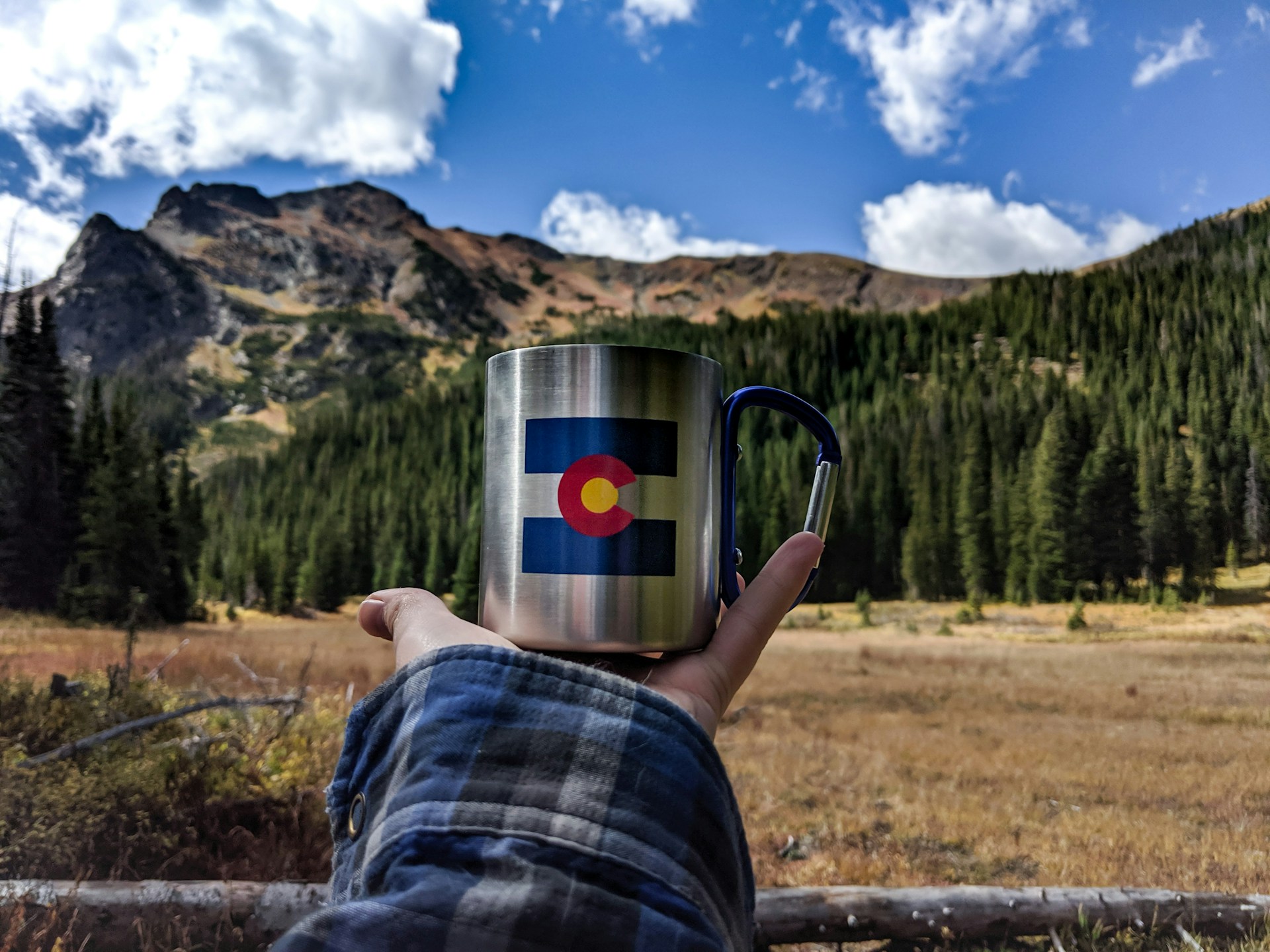 white blue and red ceramic mug on brown grass field