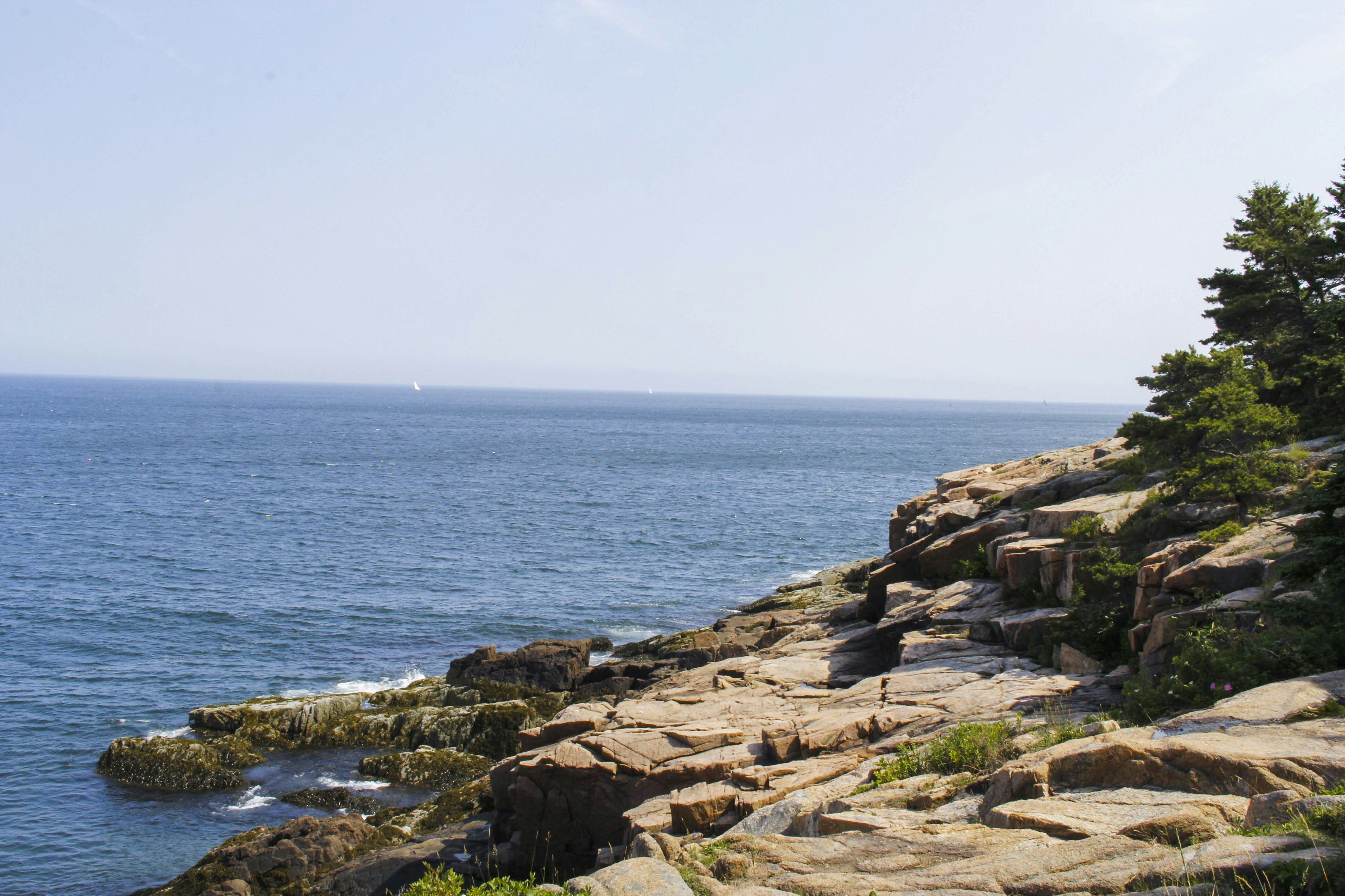 brown rocky shore with blue sea under blue sky during daytime, 