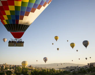 A group of diverse tourists enjoying a hot air balloon ride with panoramic views of mountains and rivers