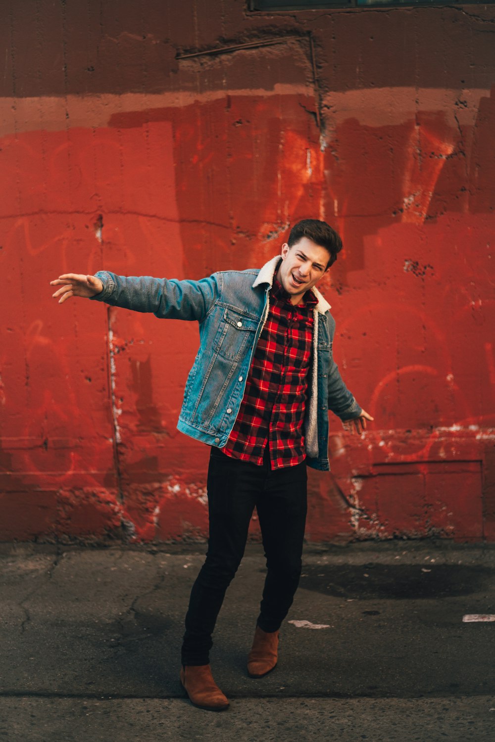 girl in blue denim jacket standing beside red wall