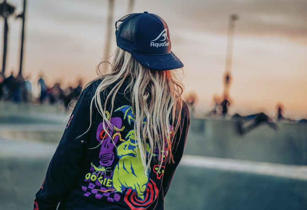 woman in blue fitted cap and black pink and green floral shirt