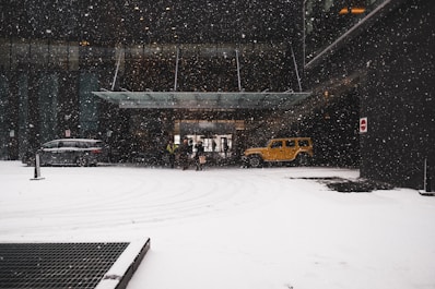 A friendly staff member greeting a vehicle occupant at the parking entrance during a snowy evening.