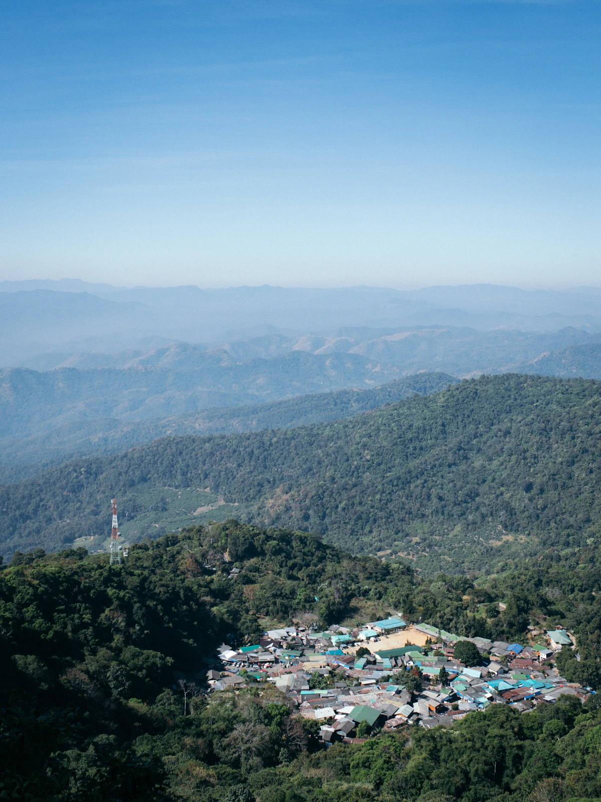 A hill village in the forest below layers of hazy ridges near Chiang Mai