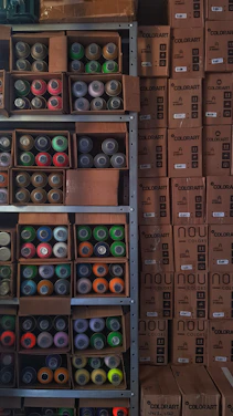 A warm, bright photo of the Ney Pinturas team happily assisting customers in a colorful store filled with paint cans.