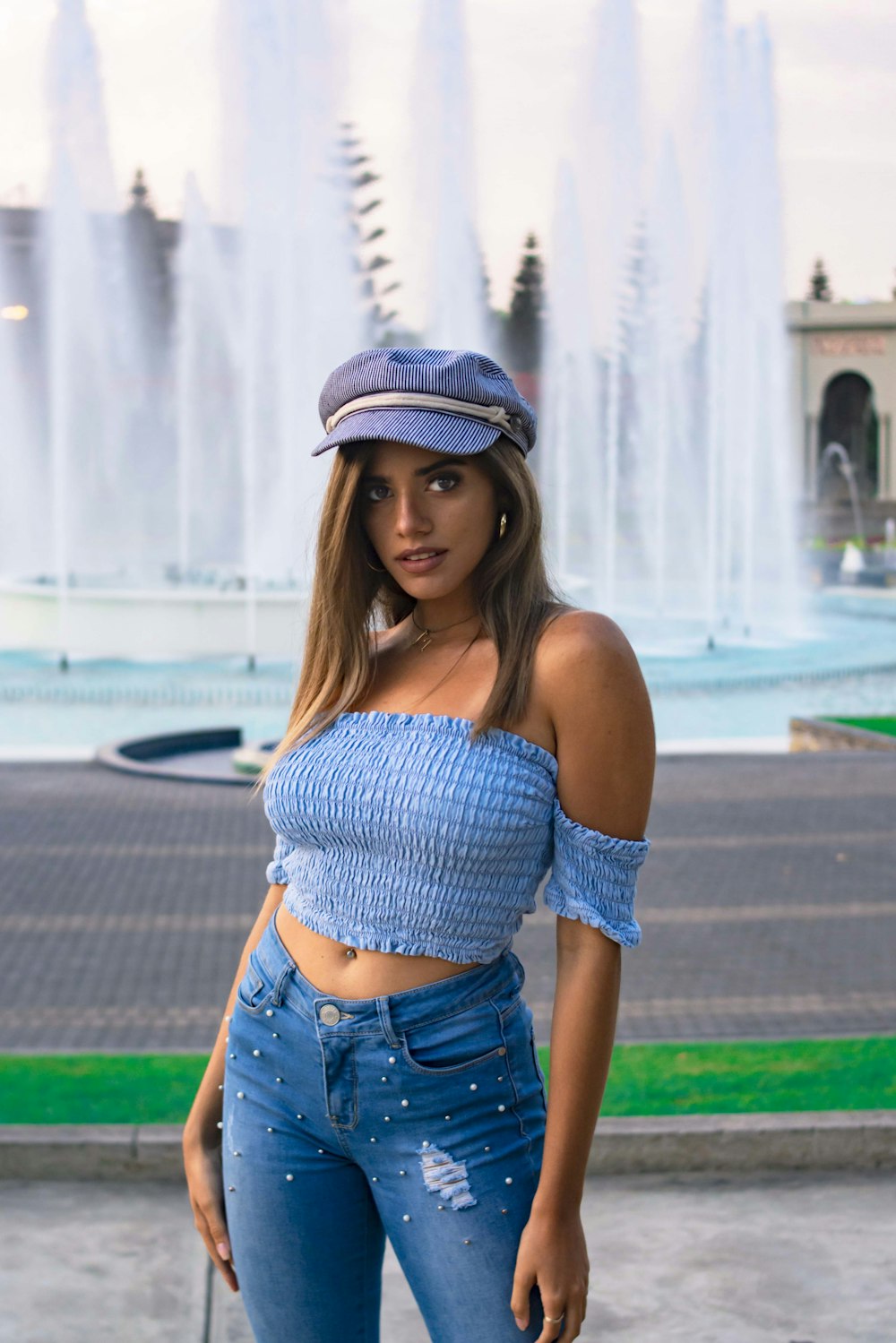 woman in blue denim shorts and white and black hat standing on green grass field during