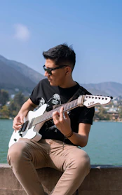 man in black crew neck t-shirt playing white electric guitar