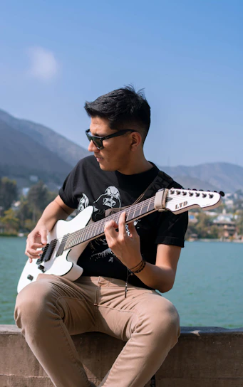 man in black crew neck t-shirt playing white electric guitar