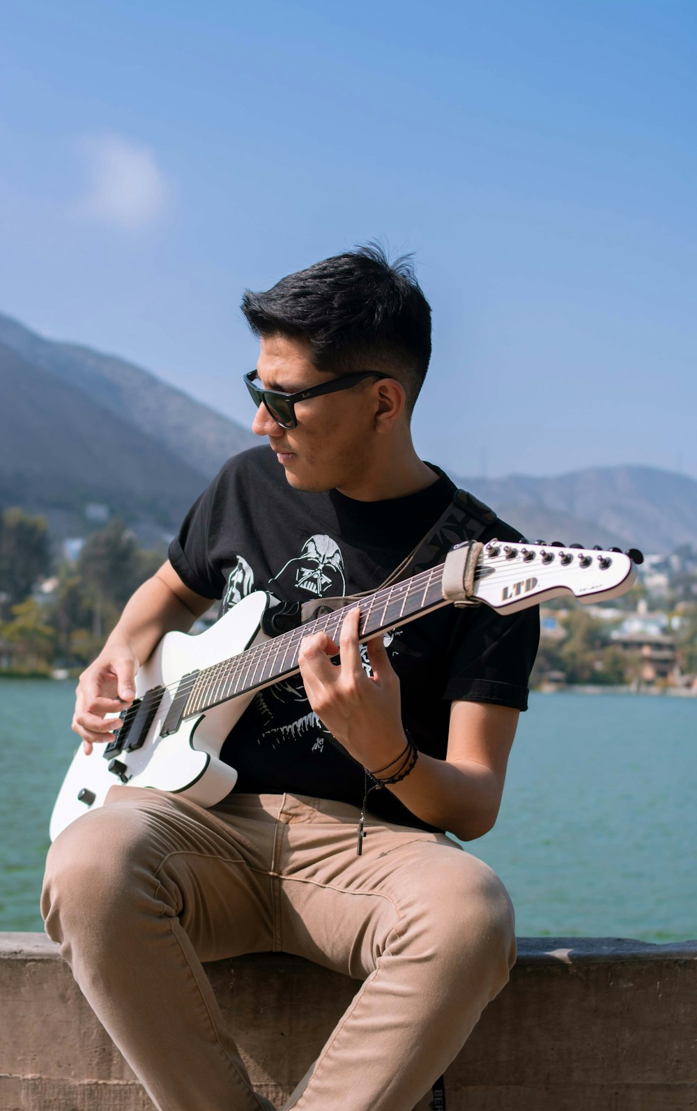 Mann im schwarzen Rundhals-T-Shirt spielt weiße E-Gitarre