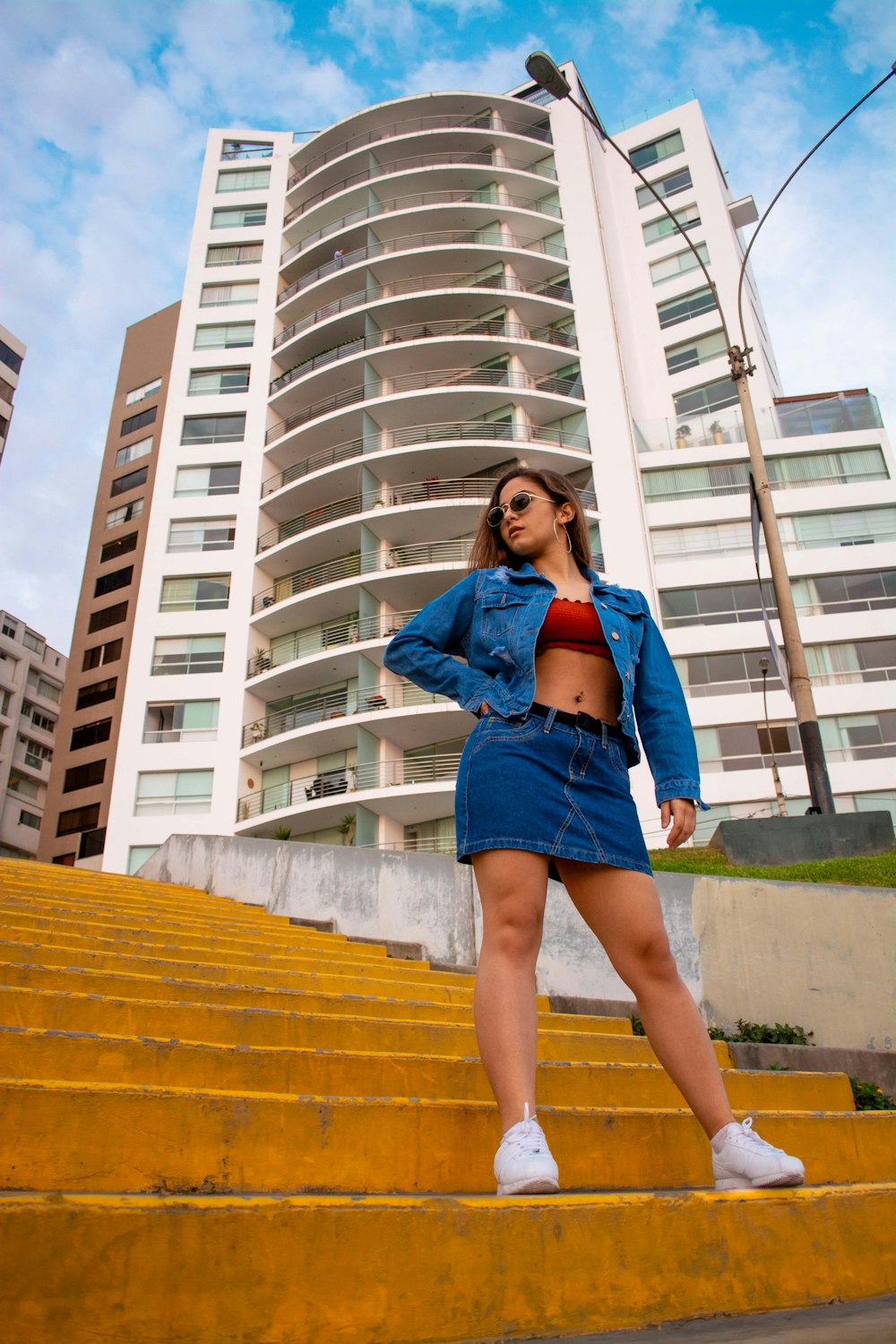 woman in blue denim jacket and blue denim shorts standing on brown wooden stairs