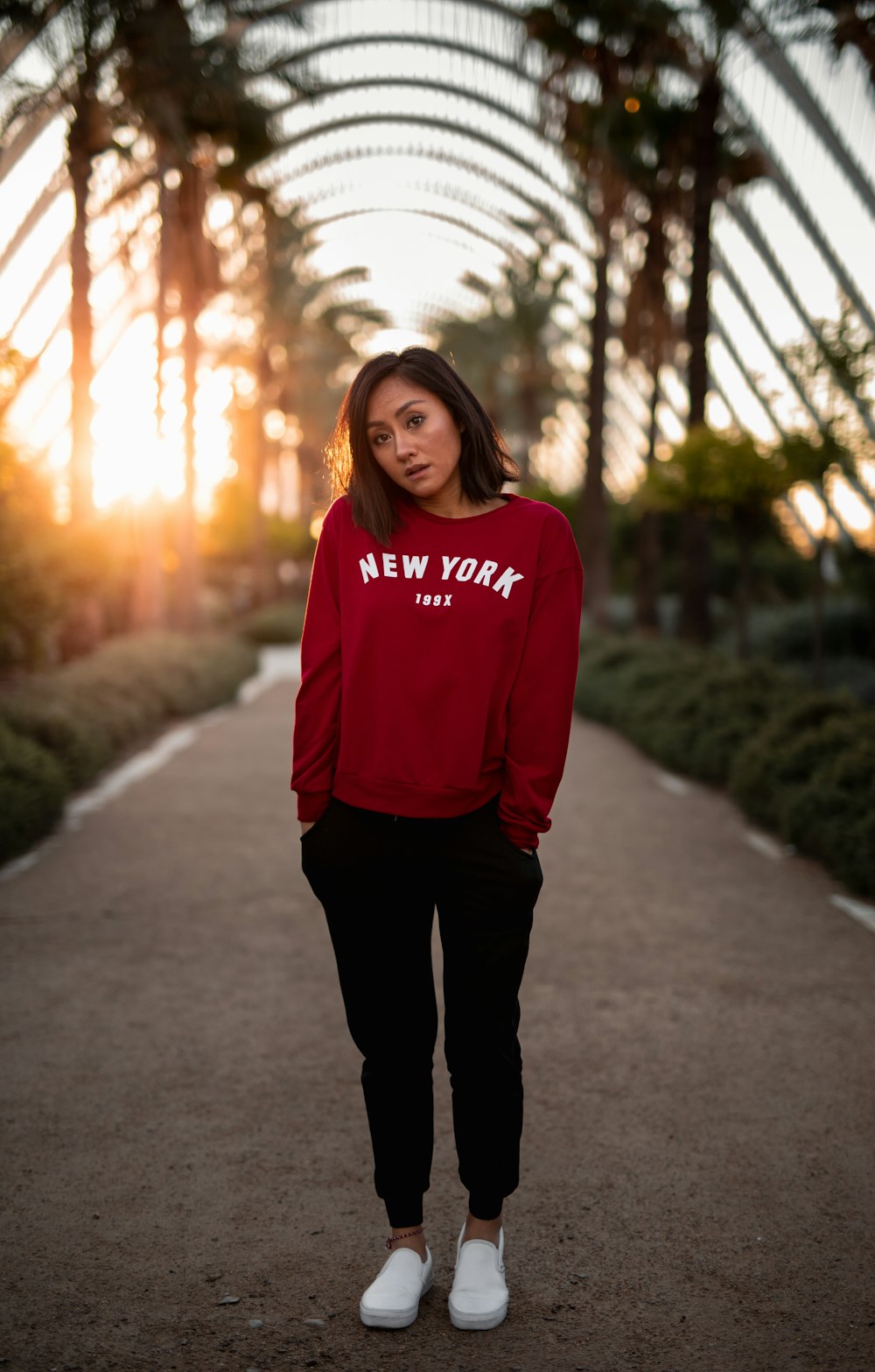 woman in pink sweater standing on road during daytime