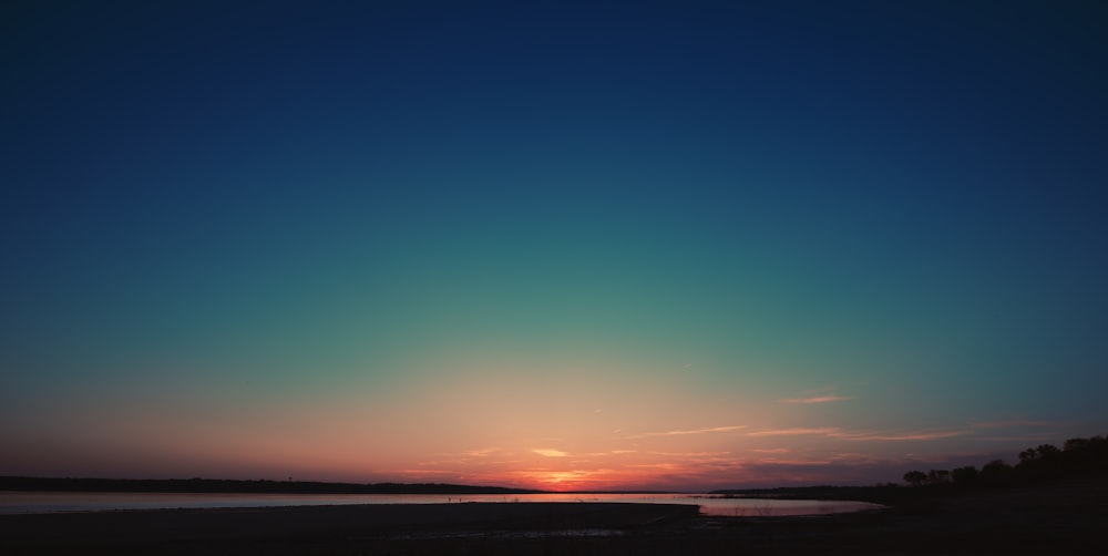 Cuerpo de agua bajo el cielo azul durante la puesta del sol