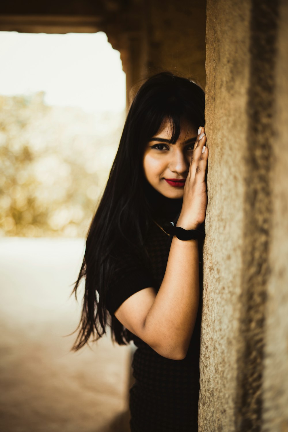 woman in black tank top leaning on brown concrete wall during daytime