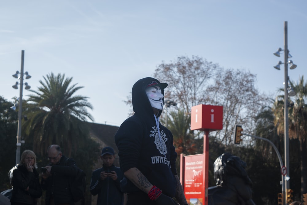 man in black hoodie standing near green palm tree during daytime