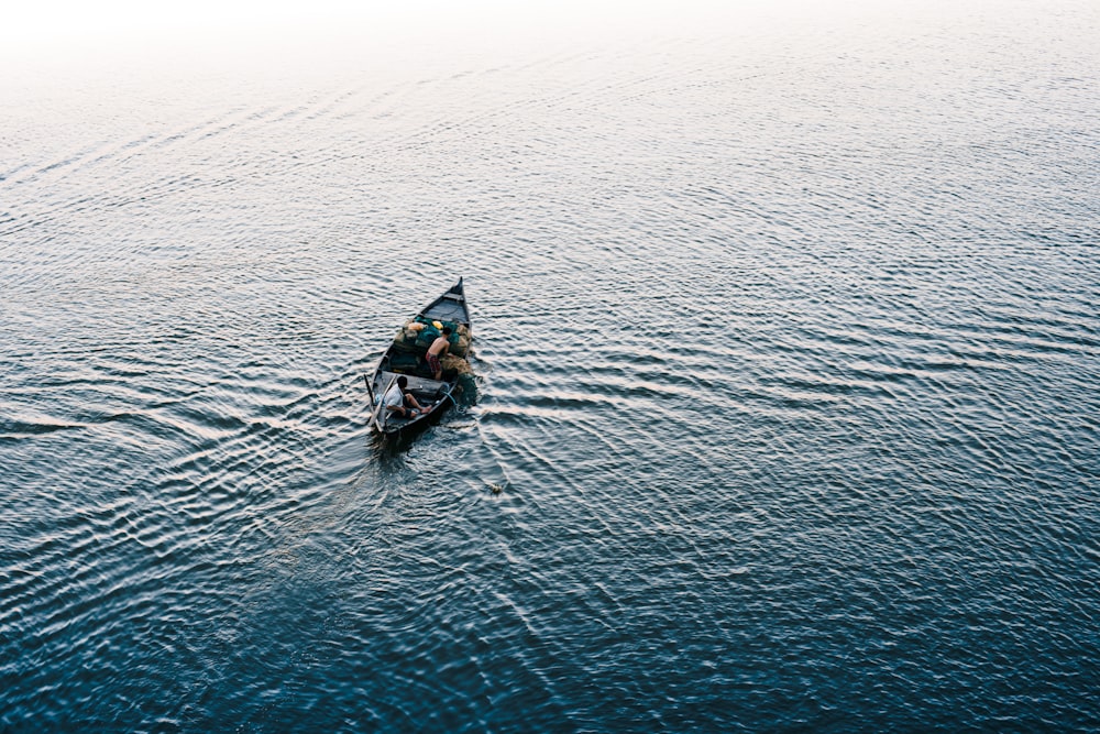 person riding on black kayak on body of water during daytime