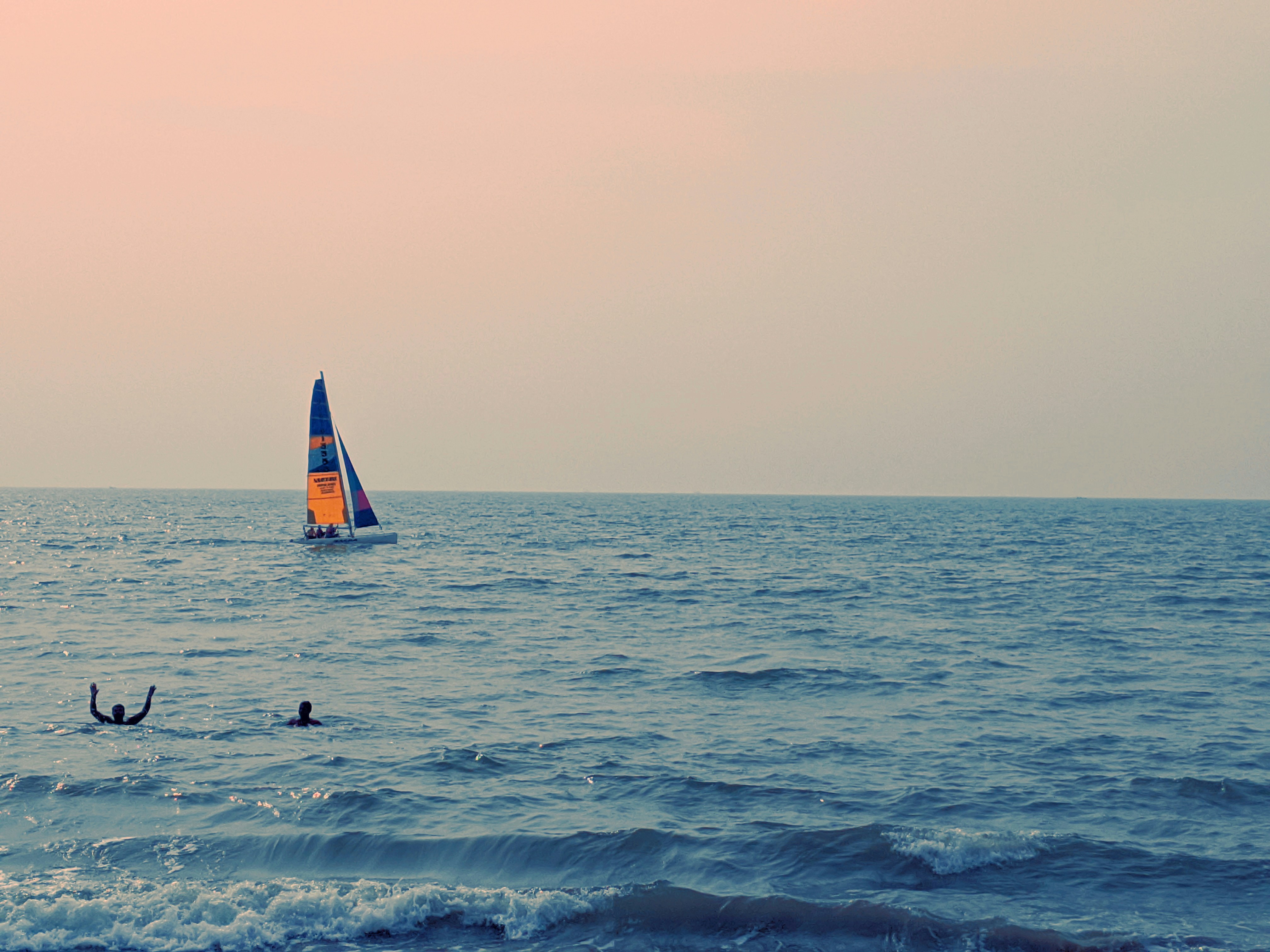 Persona con camisa negra que viaja en un velero en el mar durante el día