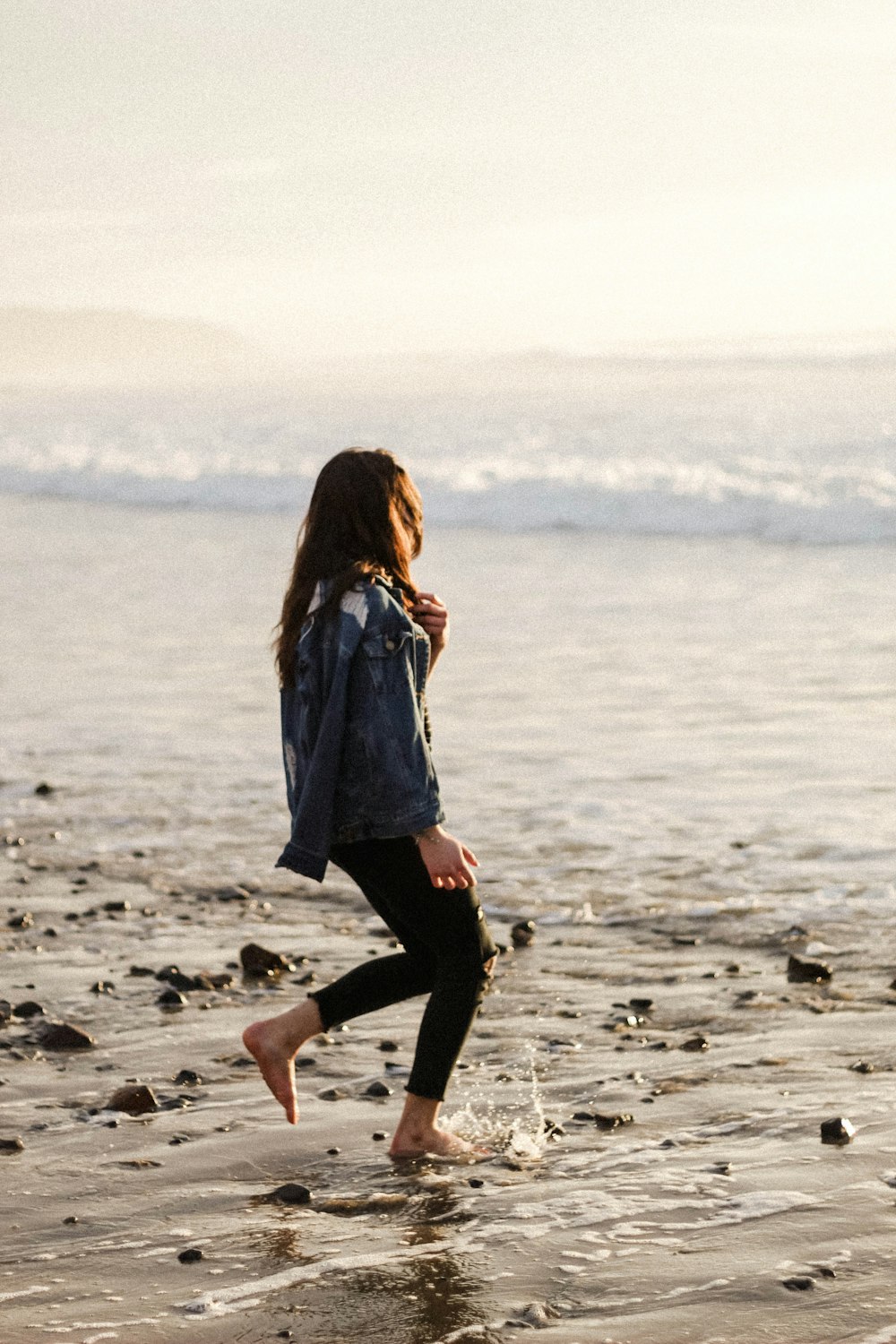 woman in blue dress walking on beach during daytime