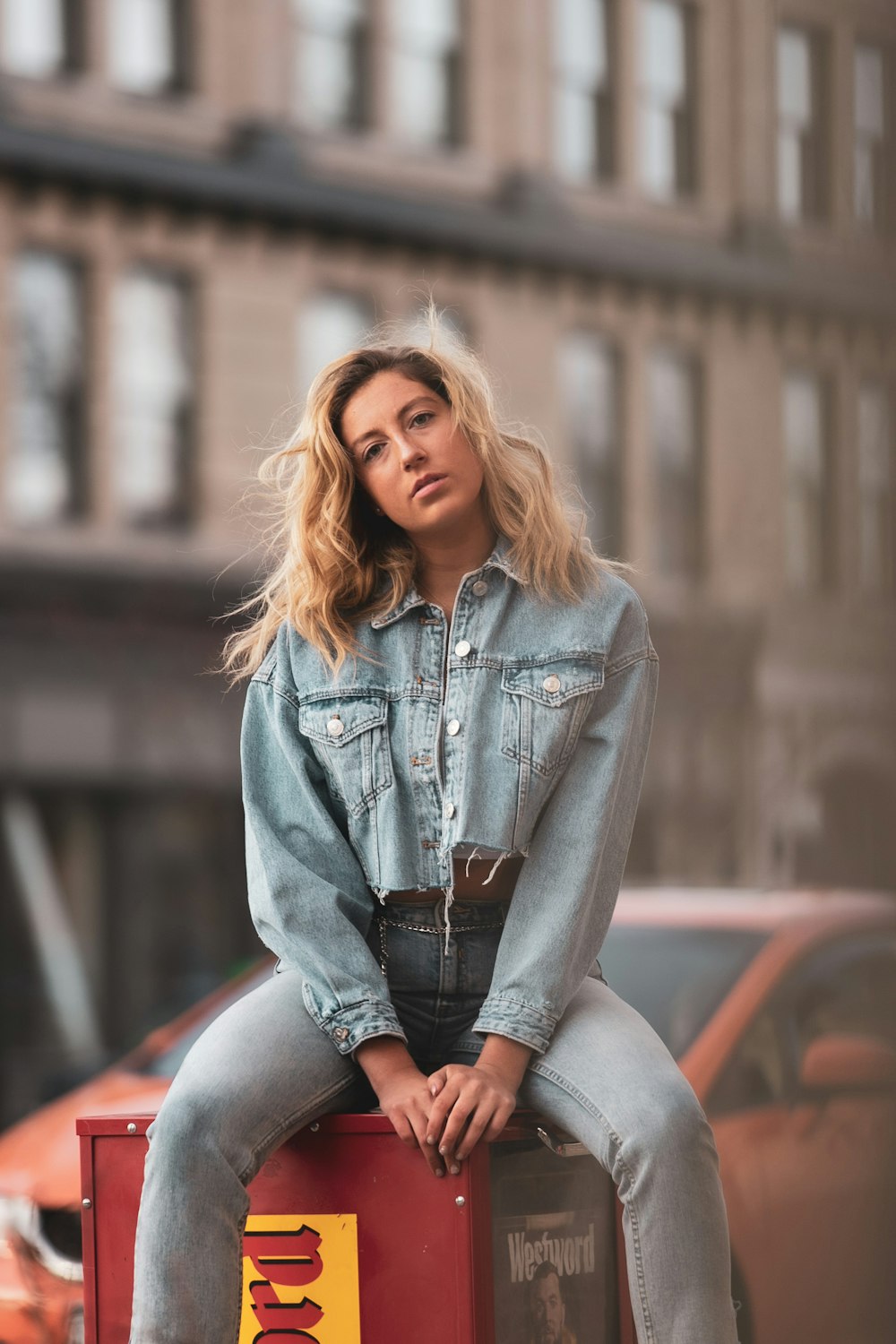 woman in blue denim jacket and black leggings sitting on brown wooden bench during daytime