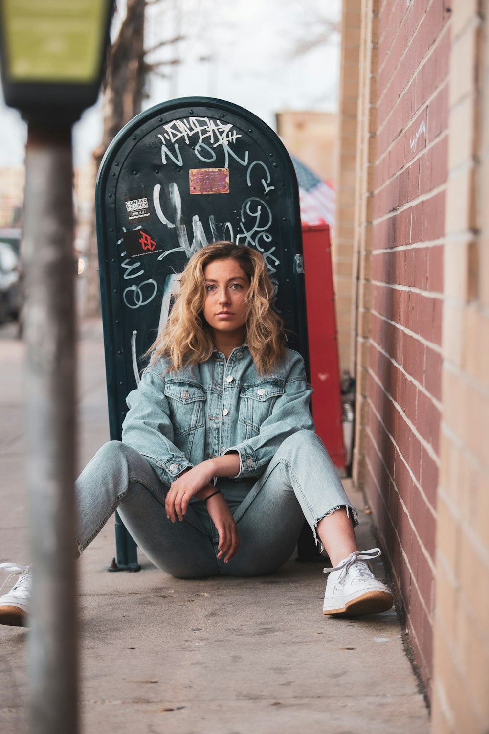 woman in blue denim jacket and gray pants sitting on red metal bar