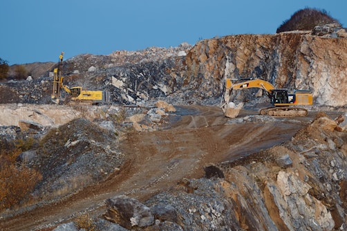 yellow and black excavator on brown rocky mountain during daytime