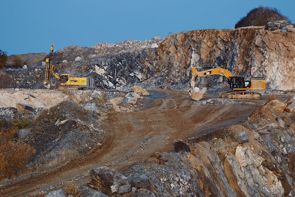 yellow and black excavator on brown rocky mountain during daytime