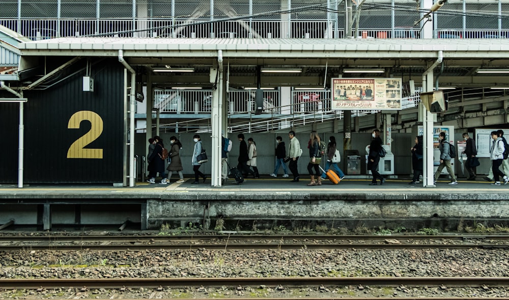 persone sedute sulla stazione ferroviaria durante il giorno