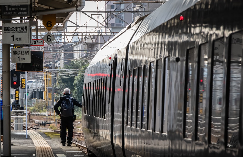 man in black jacket standing beside train