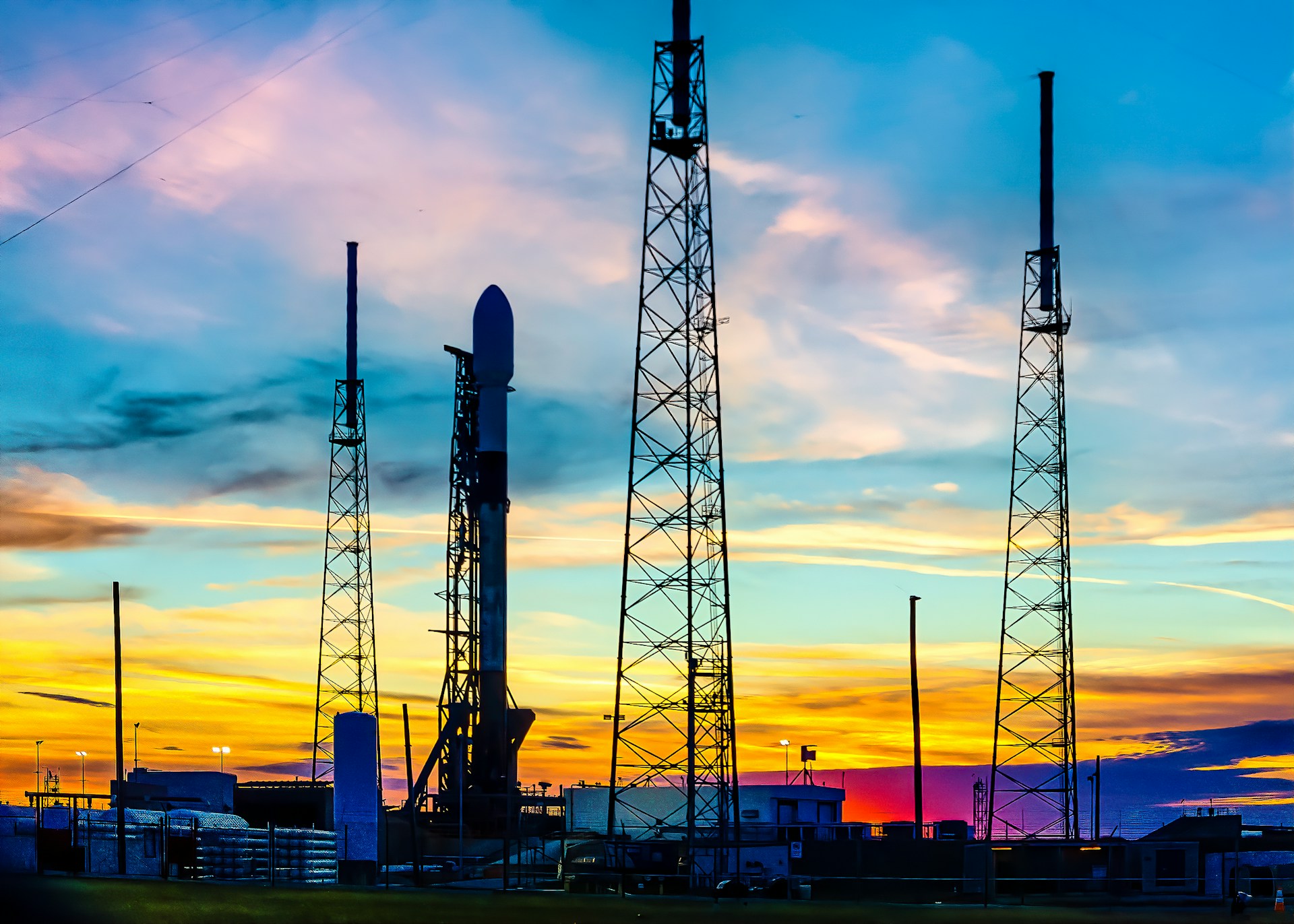 A panoramic view of a rocket launch pad at sunset, with the rocket poised for takeoff against a colorful sky.