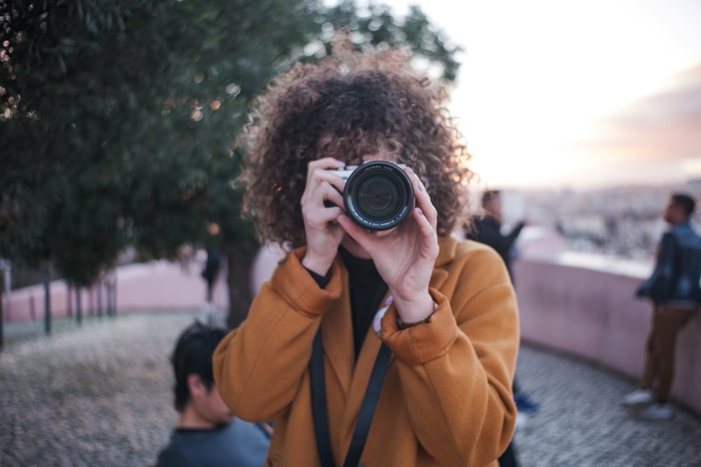 man in orange jacket holding camera