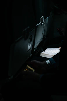 A cozy traveler reading a glowing tablet in a bustling airport lounge filled with plants and warm light.