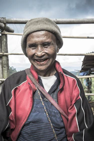 An elderly person smiling warmly while receiving assistance from a caregiver.