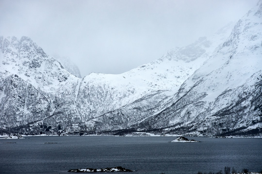 snow covered mountain near body of water