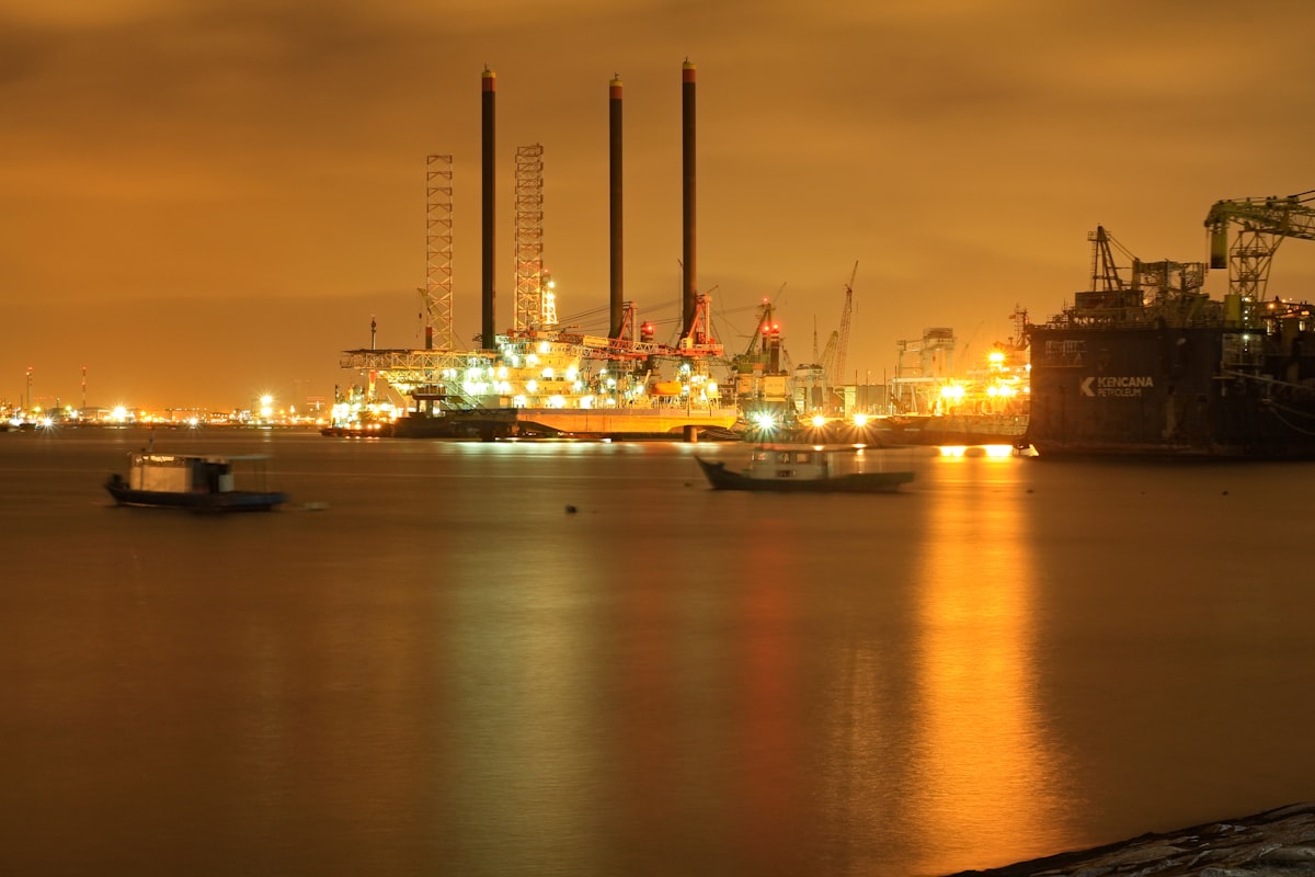Oil refinery illuminated at night reflected in water