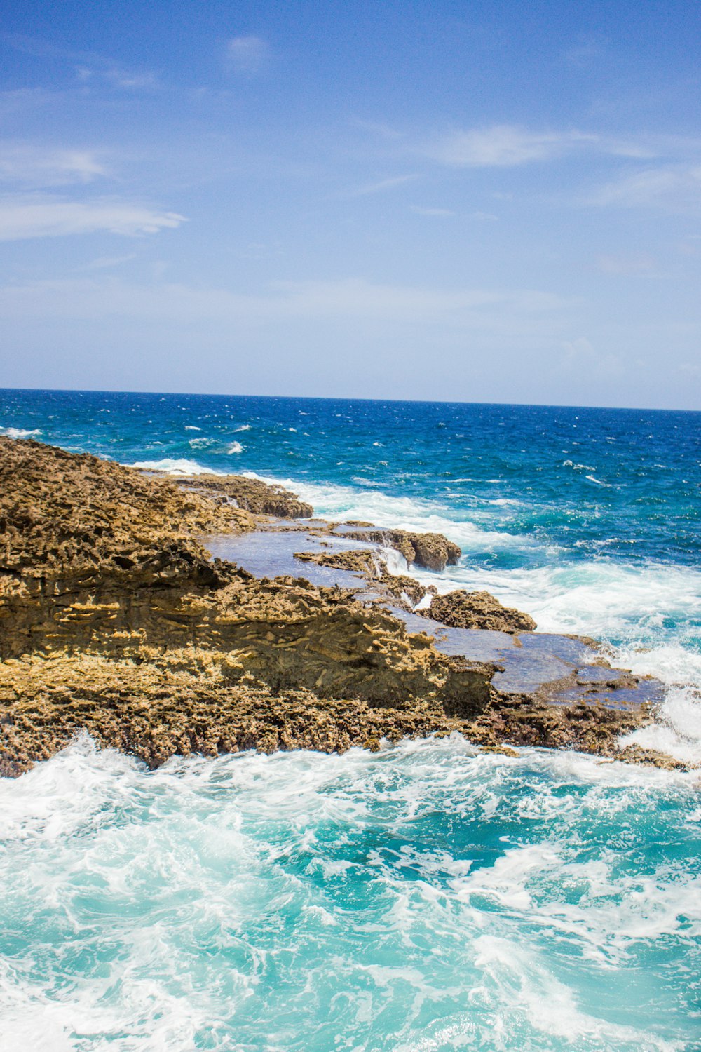 昼間の青空の下での茶色の岩だらけの海岸