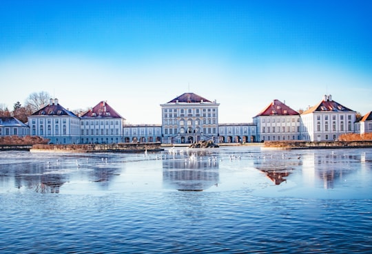 white and brown concrete building near body of water during daytime in Schlosspark Nymphenburg Germany