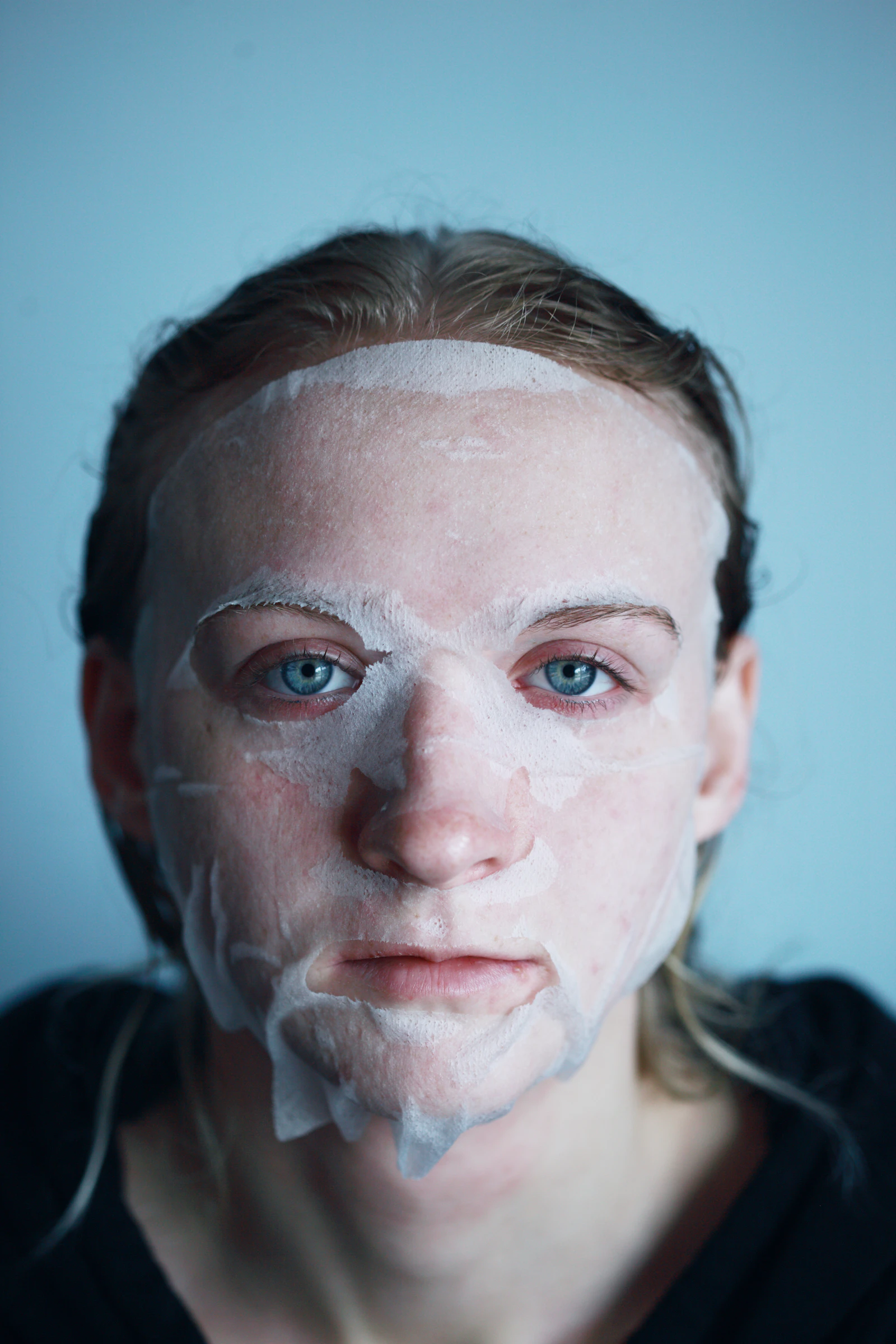 Femme appliquant un masque en tissu sur son visage, soin de la peau