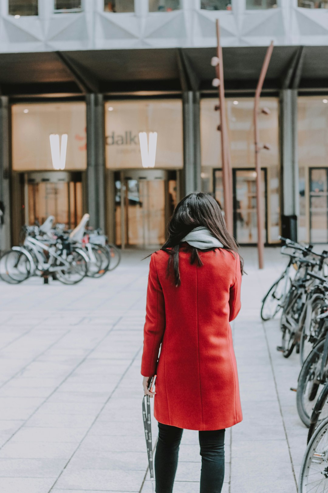 woman in red coat walking on sidewalk during daytime