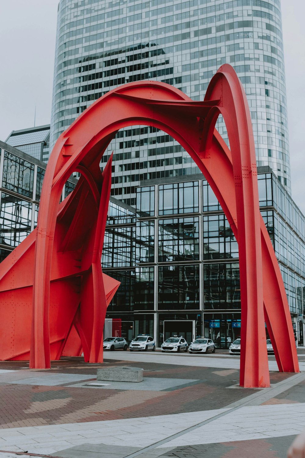 arco de metal rojo cerca de un edificio de hormigón gris durante el día