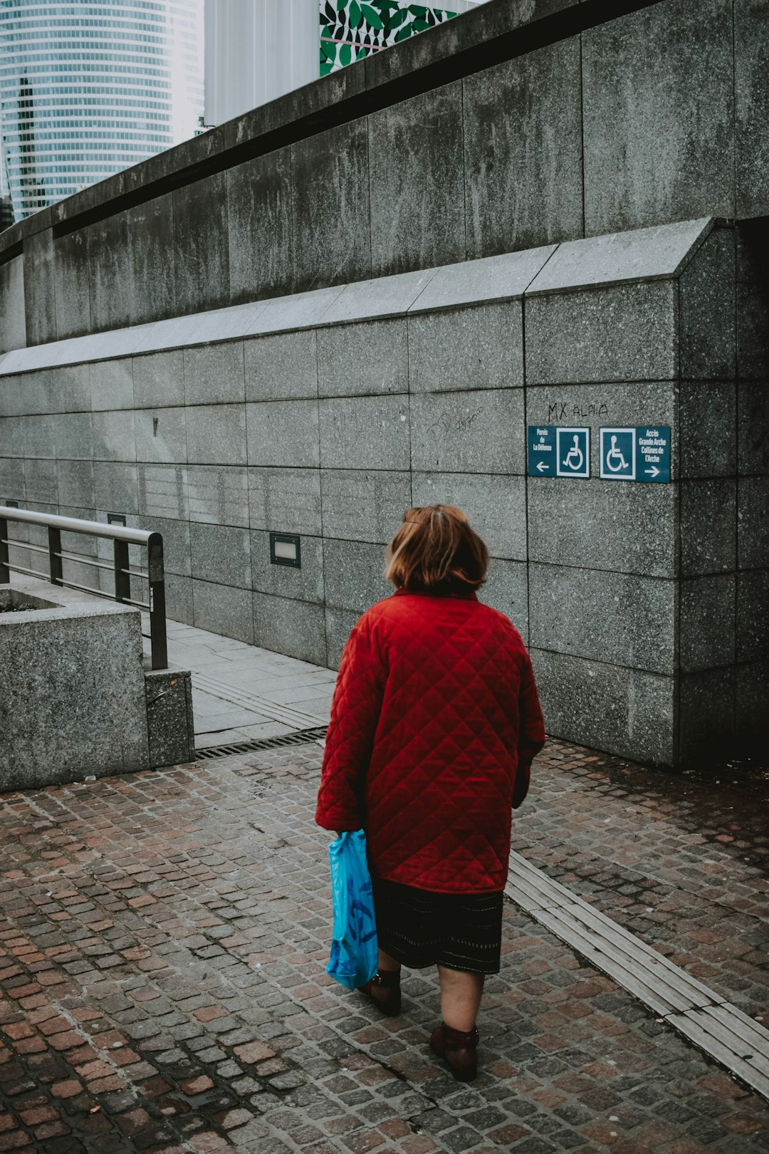 woman in red sweater walking on sidewalk during daytime