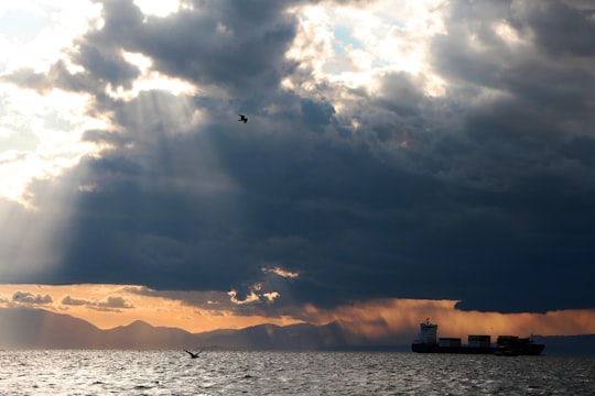 silhouette of boat on sea under cloudy sky during sunset in Thessaloniki Greece