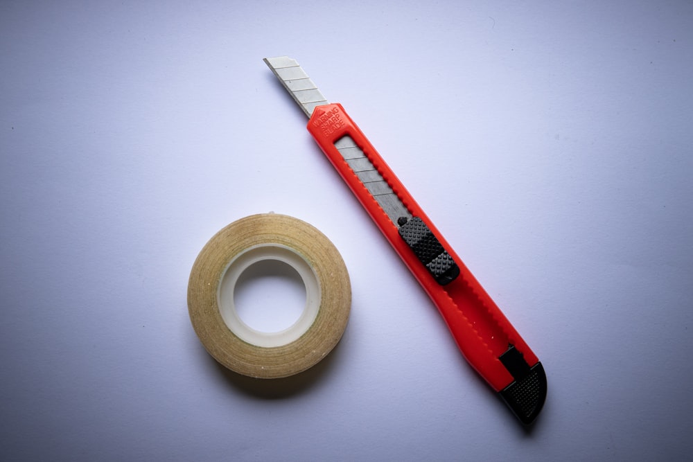 赤と黒のクリックペン、白いテープロールの横