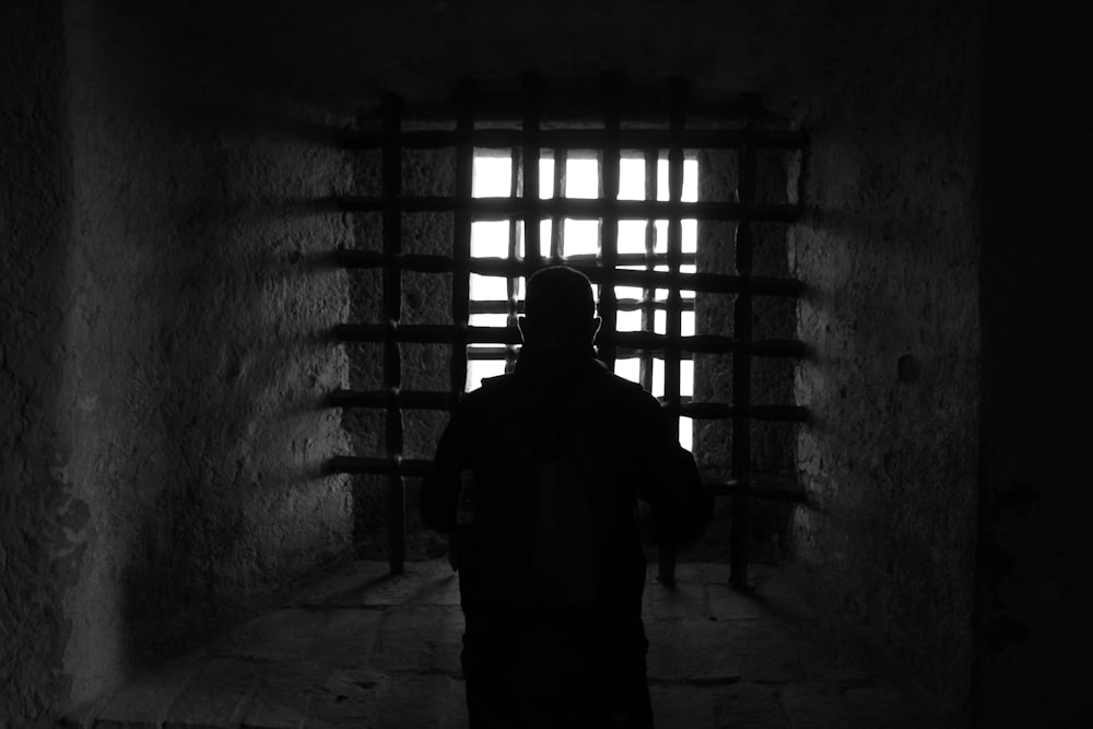 silhouette of man standing in front of window