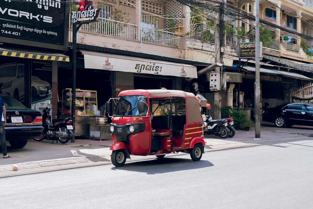 red and black auto rickshaw parked on sidewalk during daytime