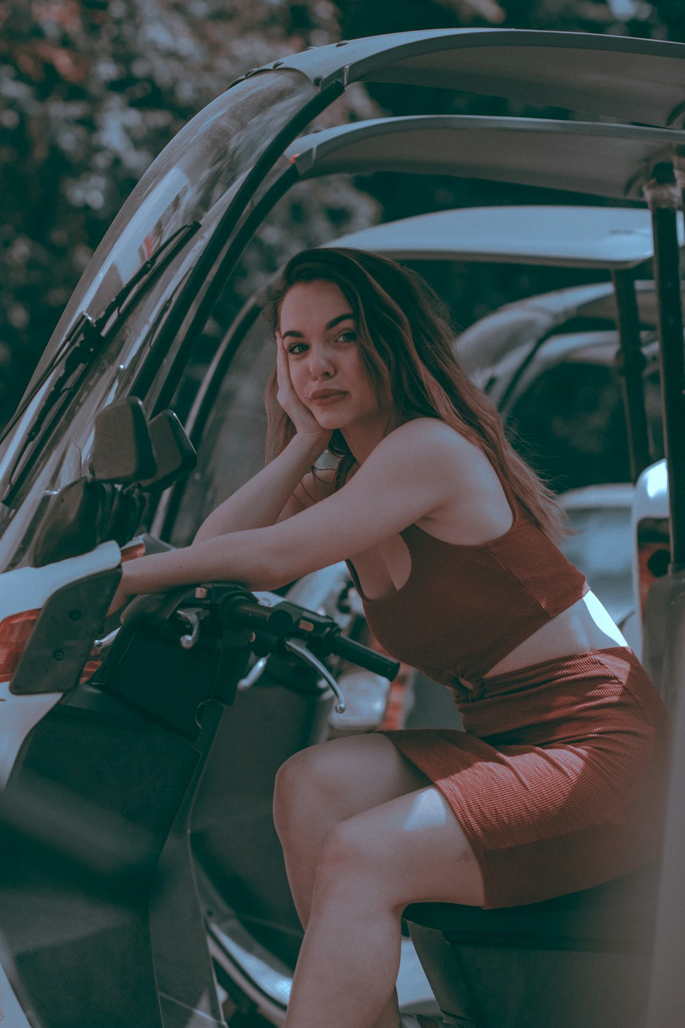 woman in red tank top and red shorts sitting on black car