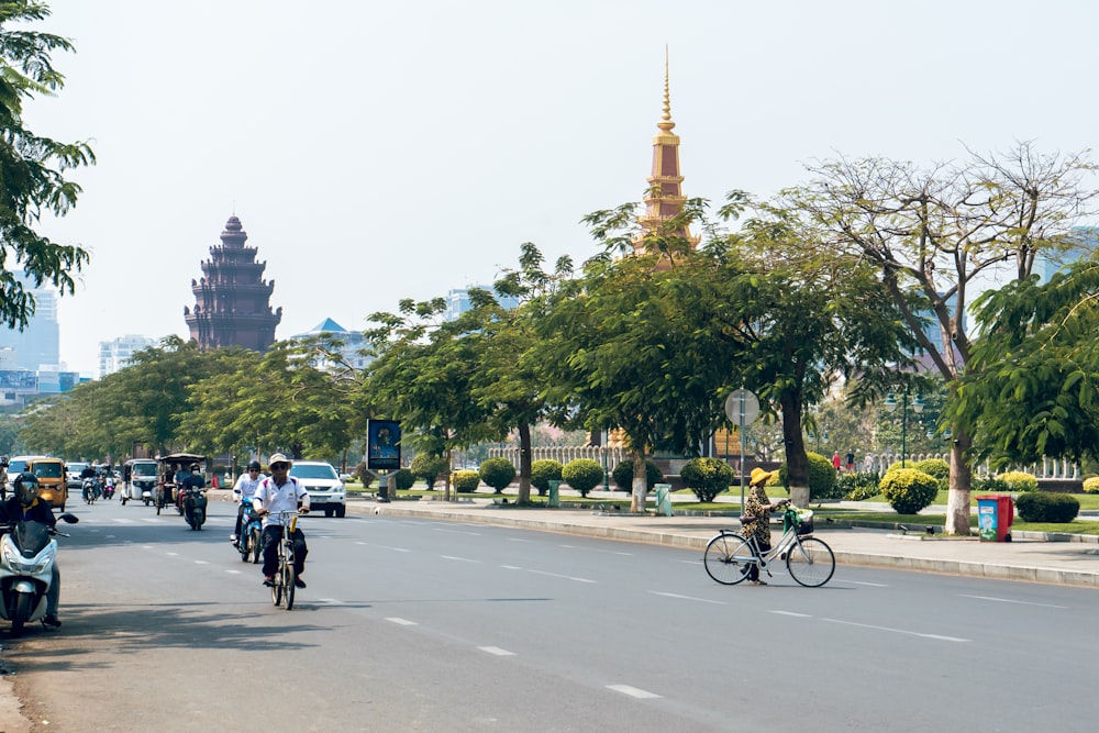 Persone che vanno in bicicletta sulla strada vicino ad alberi ed edifici durante il giorno